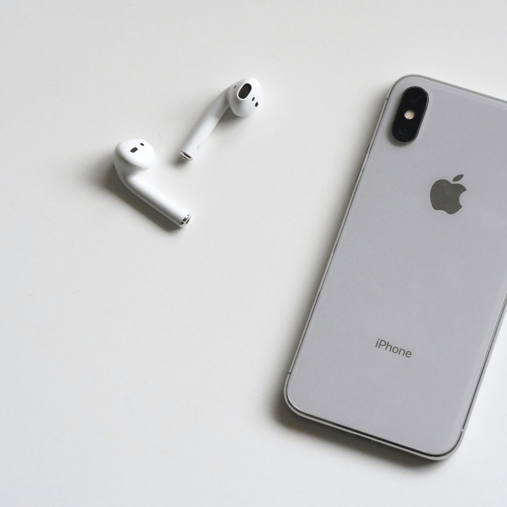 white iphone with a pair of airpods on it's left
