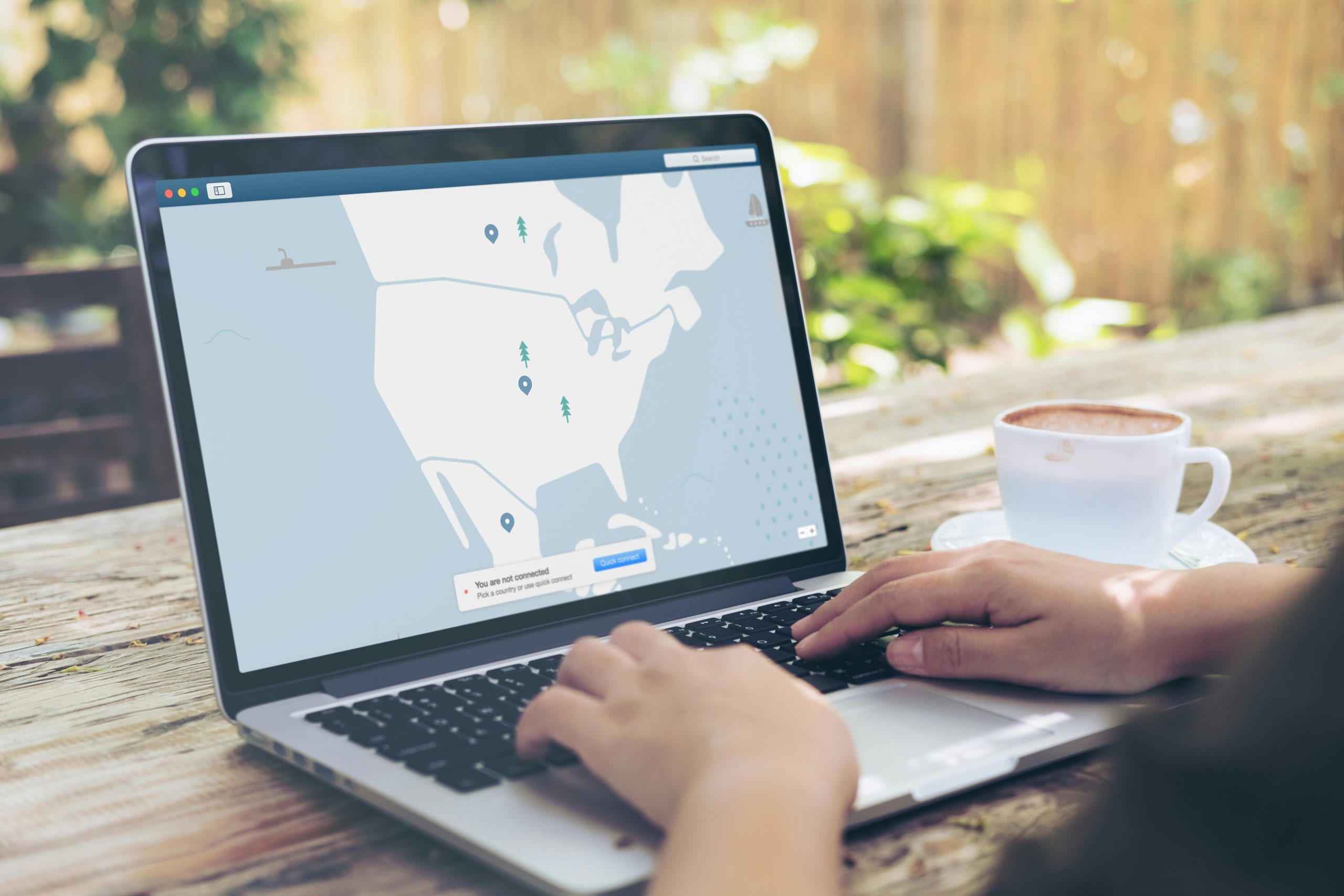 a person is sitting at the computer, with a map of VPN map open on the screen, with a coffee cup next to the computer.