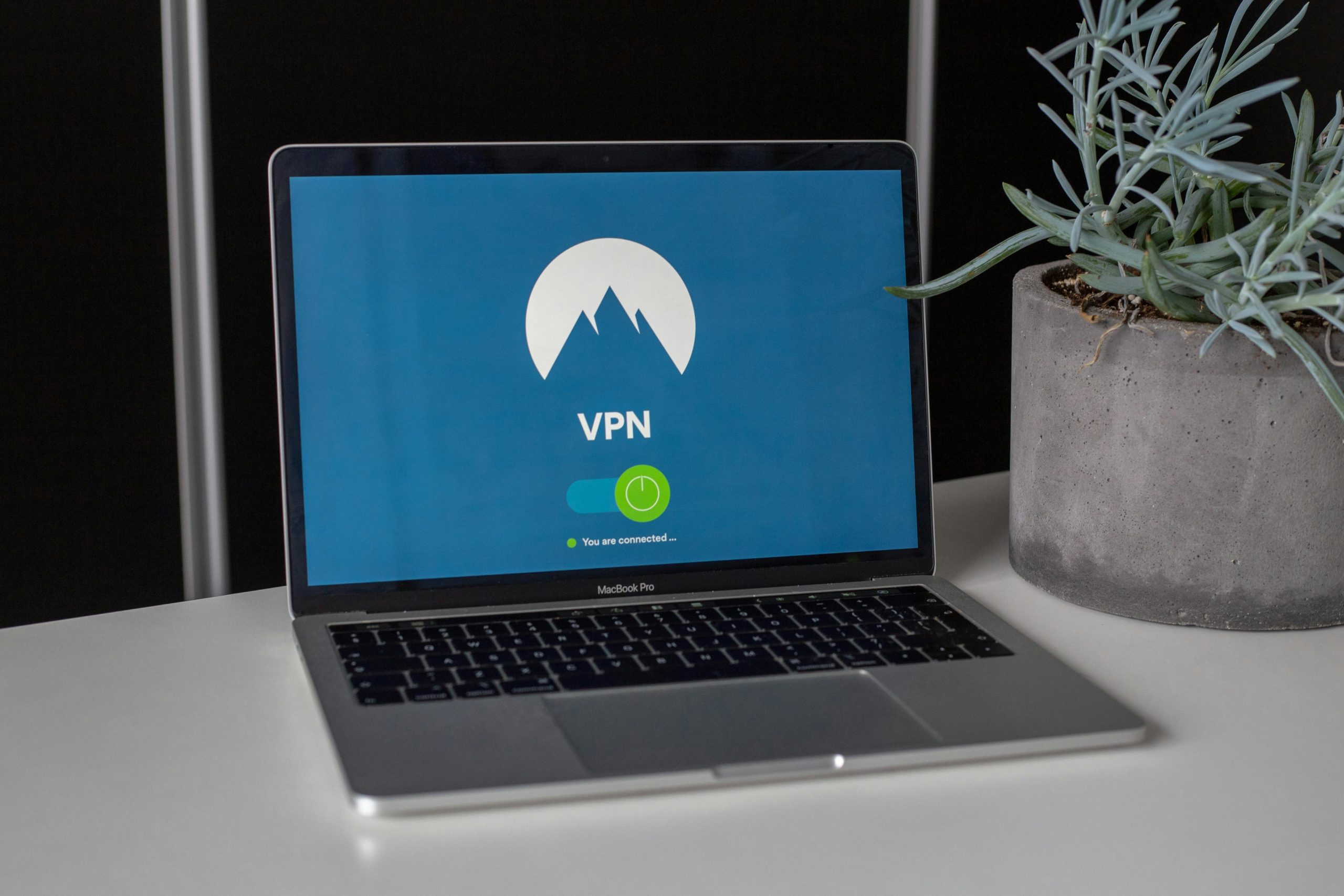 NordVPNs logo and the word VPN is visible on the screen of a macbook computer, laying on the table